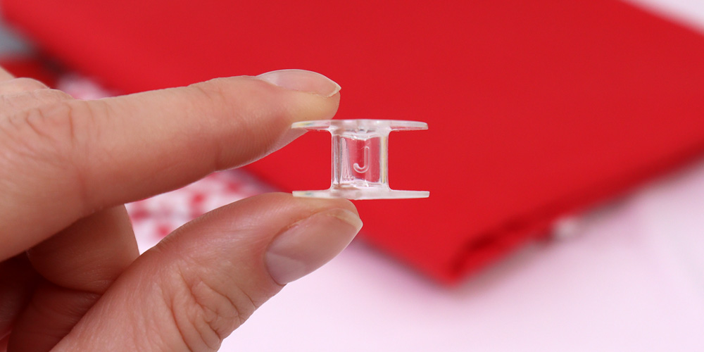 Litera J na oryginalnej szpulce Janome – znak autentyczności.